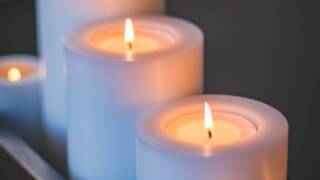 Kynttilöitä rivissä tummaa taustaa vasten.